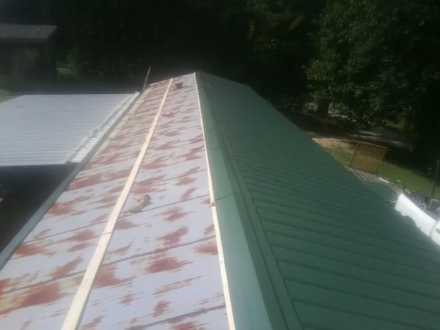 Old rusted panels beside newly installed green metal roofing — Wind Damage Roof Repair by Roofing Brothers in West Augusta