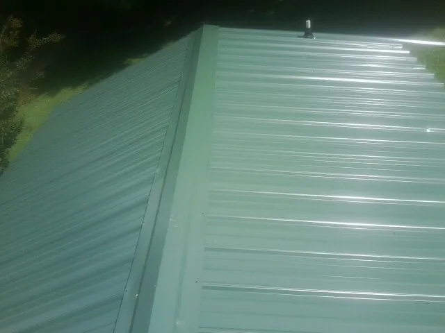 New green metal panels meeting at the ridge of a roof — Flat Roof Repair work by our crew in West Augusta