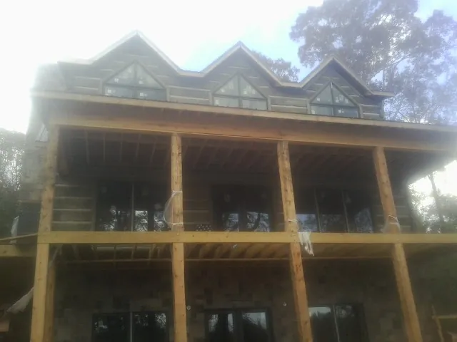Dormers and porch framing on a large log home under construction — Roof Coating work by our crew in West Augusta