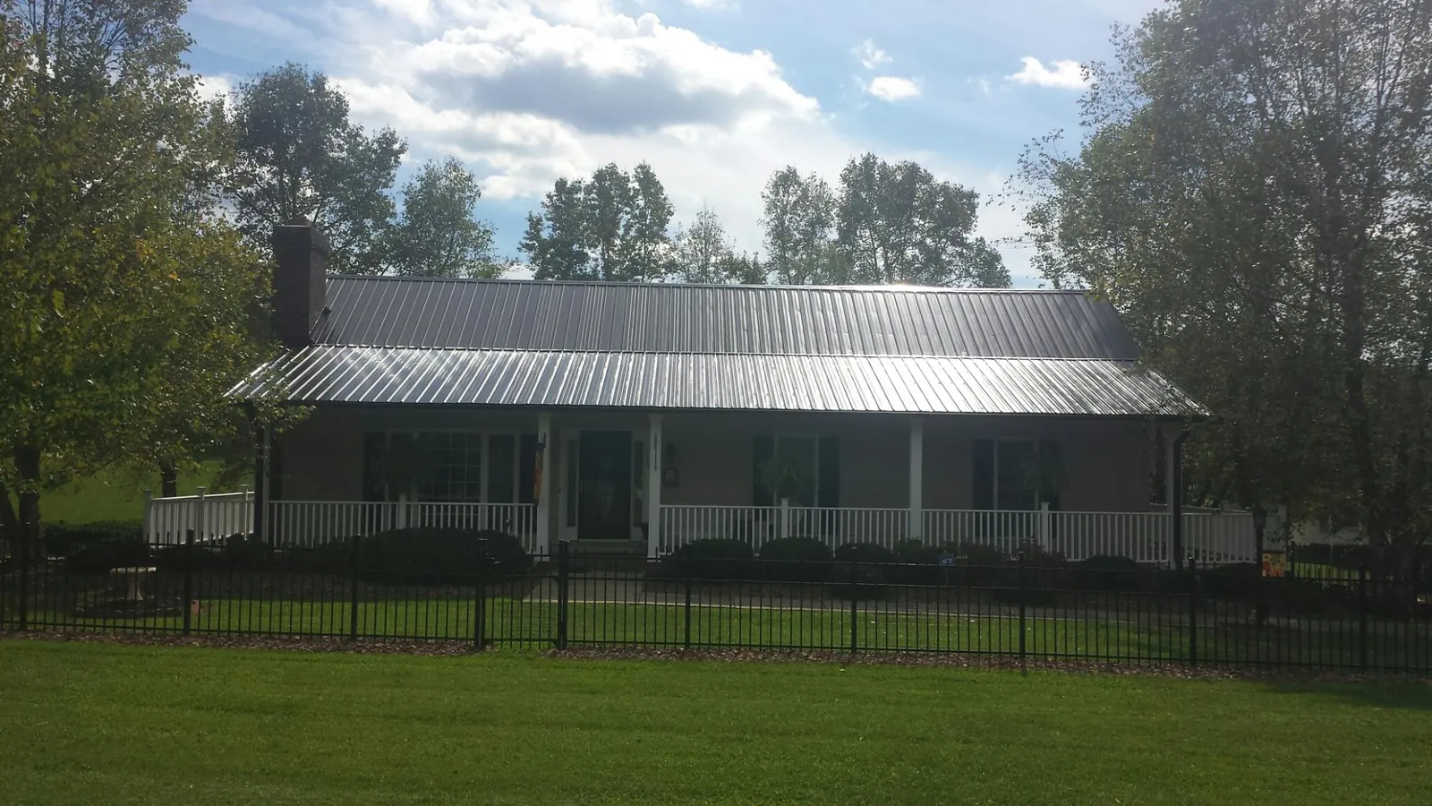 Gray metal roof on a brick ranch with a full width front porch — Gutter Guard Installation work by our crew in West Augusta