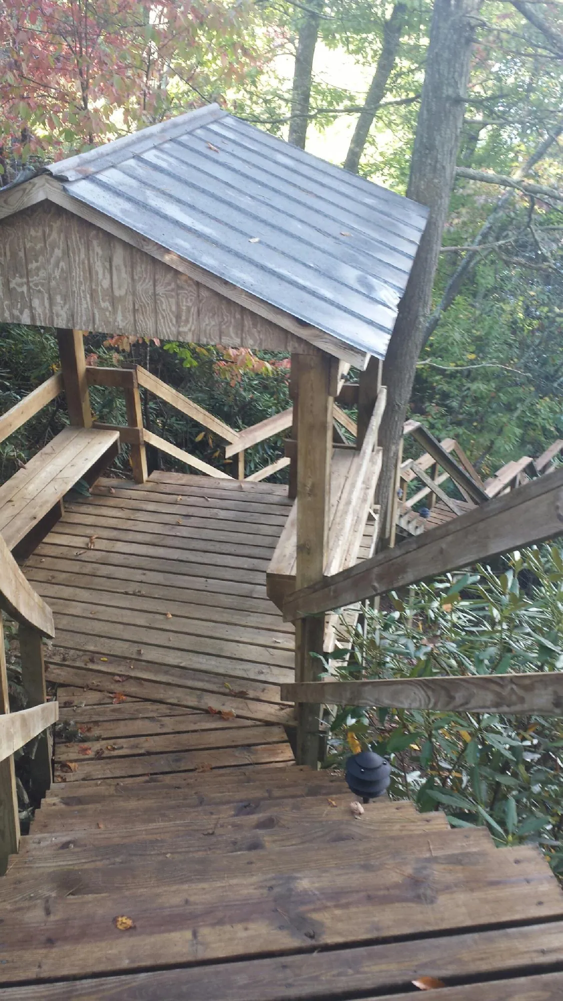 Metal roofed shelter over wooden steps on a wooded walkway — Skylight Repair & Installation work by our crew in West Augusta