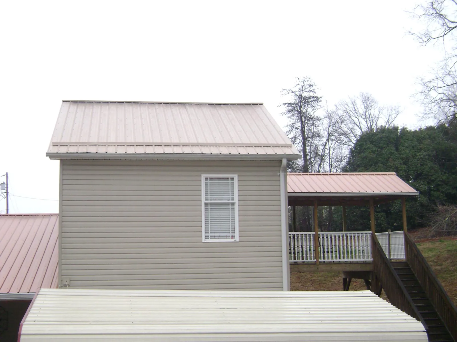 Tan metal roofs on a two story addition and attached porch, from a Roof Replacement job in West Augusta