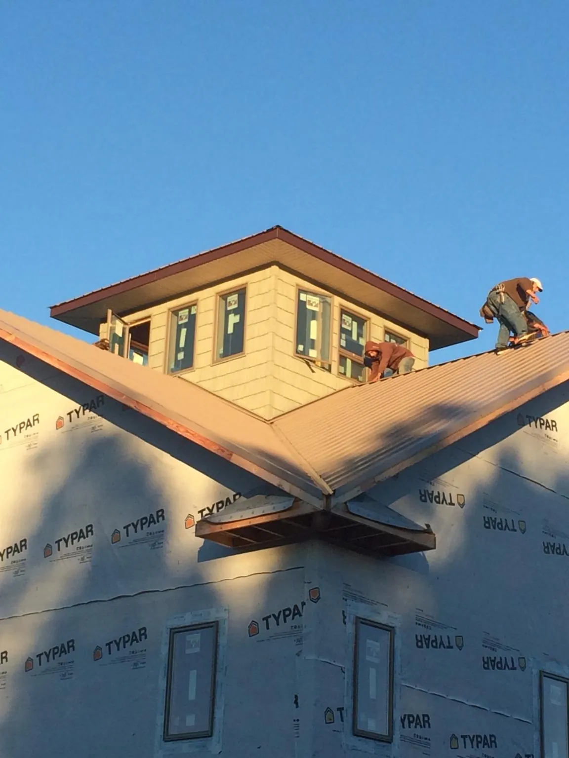 Roofers working around a rooftop cupola on a new metal roof at sunset — Roof Waterproofing in West Augusta by Roofing Brothers